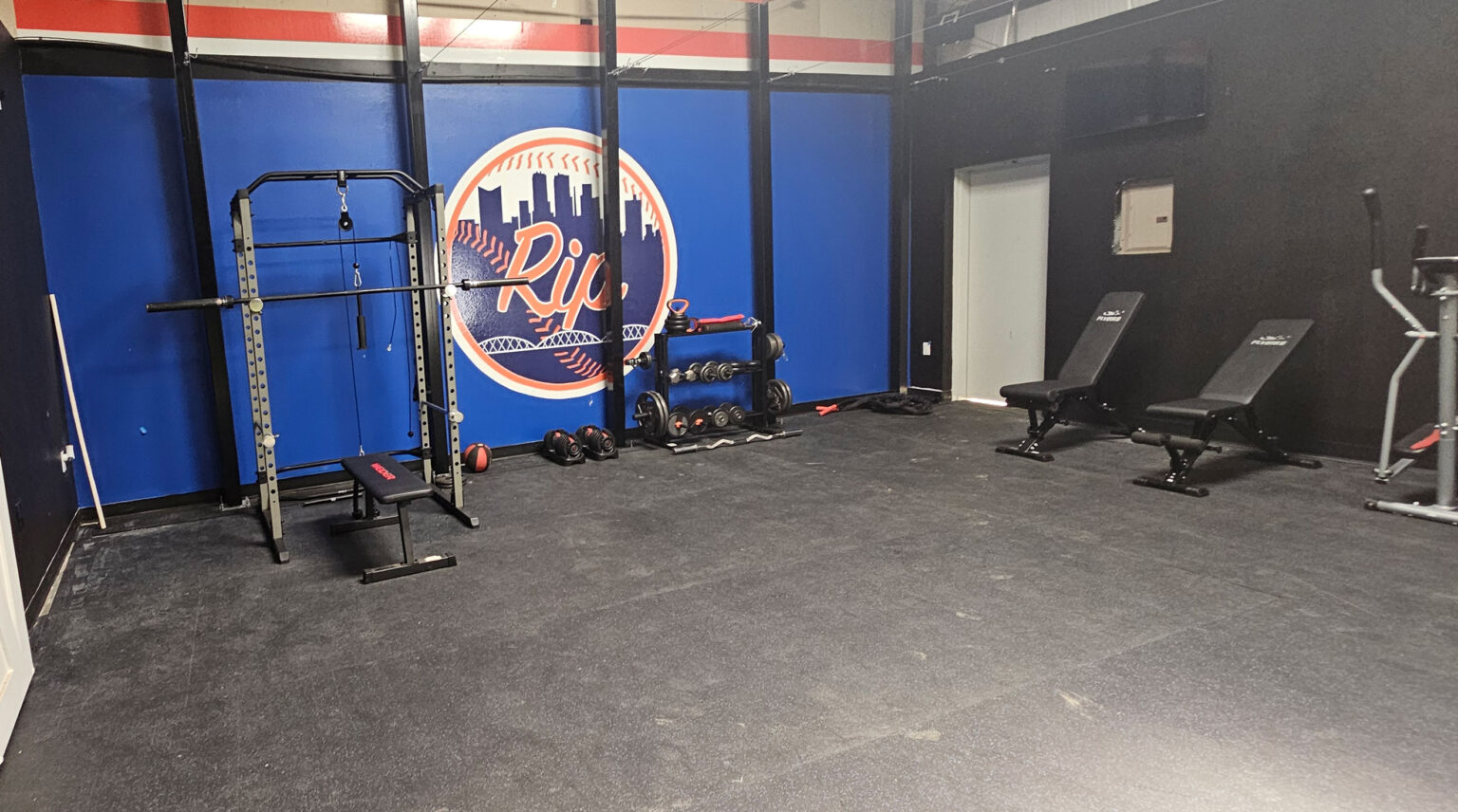 Strength and conditioning room with the Texas Rip logo mural, squat rack and free weights
